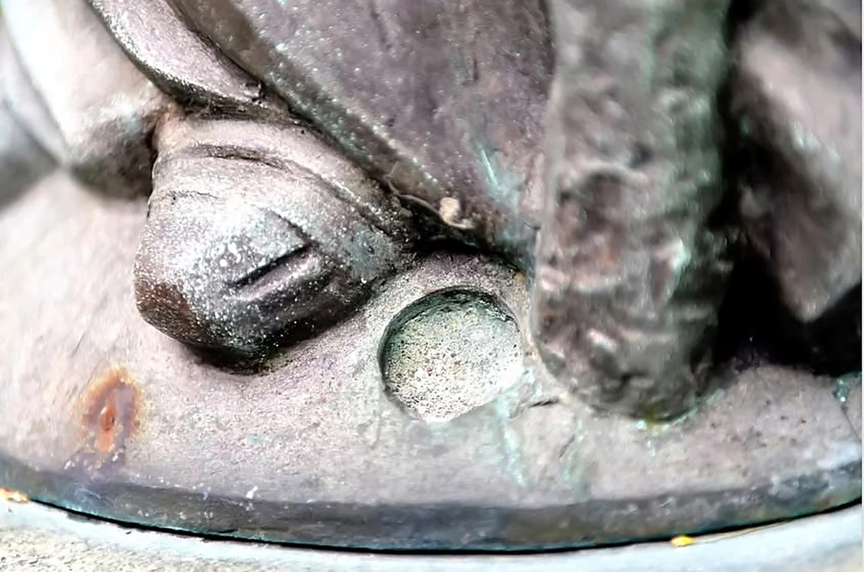 Dettaglio di un piede in bronzo e della base rotonda della statua