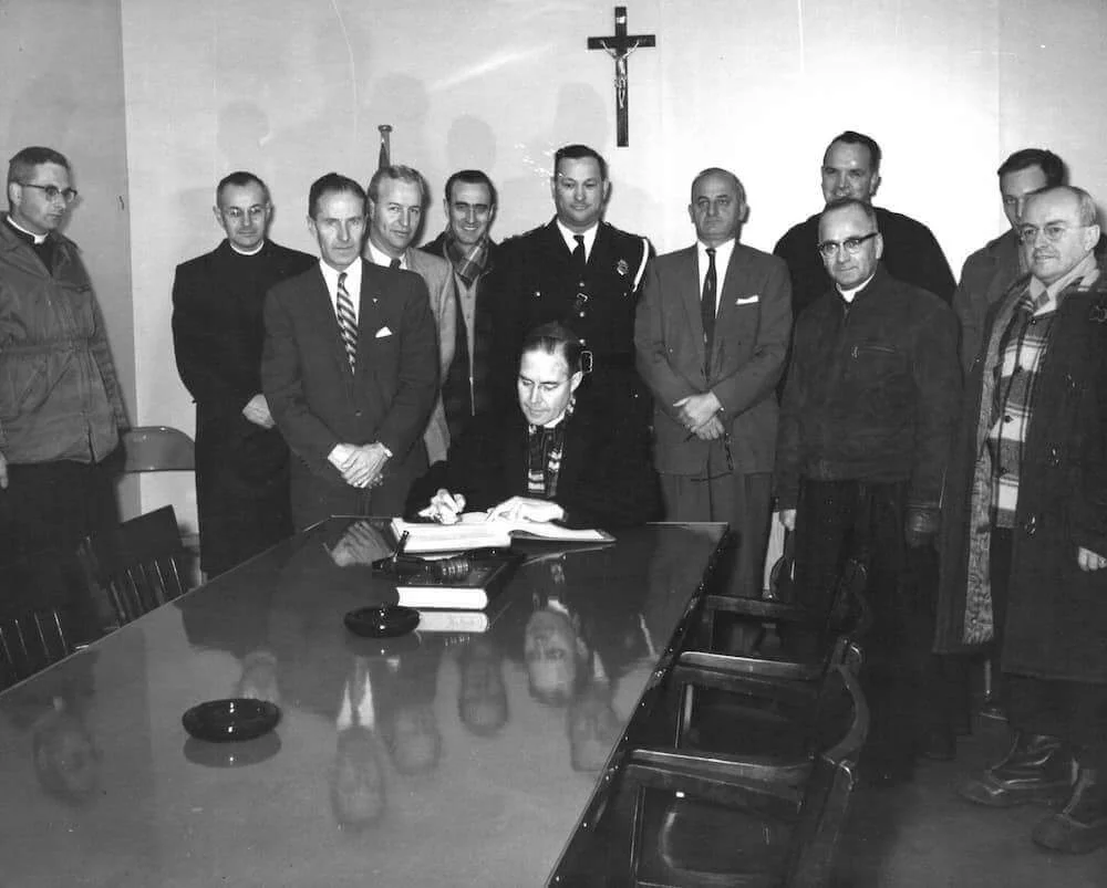 Mons. Couturier e i visitatori riuniti attorno a un tavolo